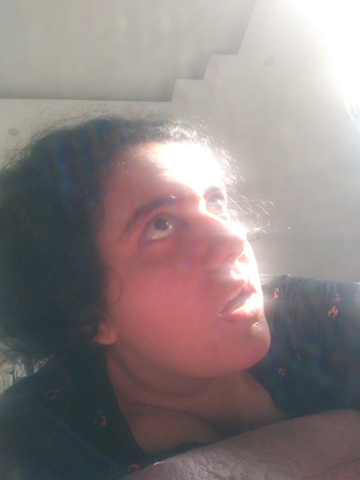 mona with their mouth agape, eyes wide open looking at the distance, their face covered by the sunlight.